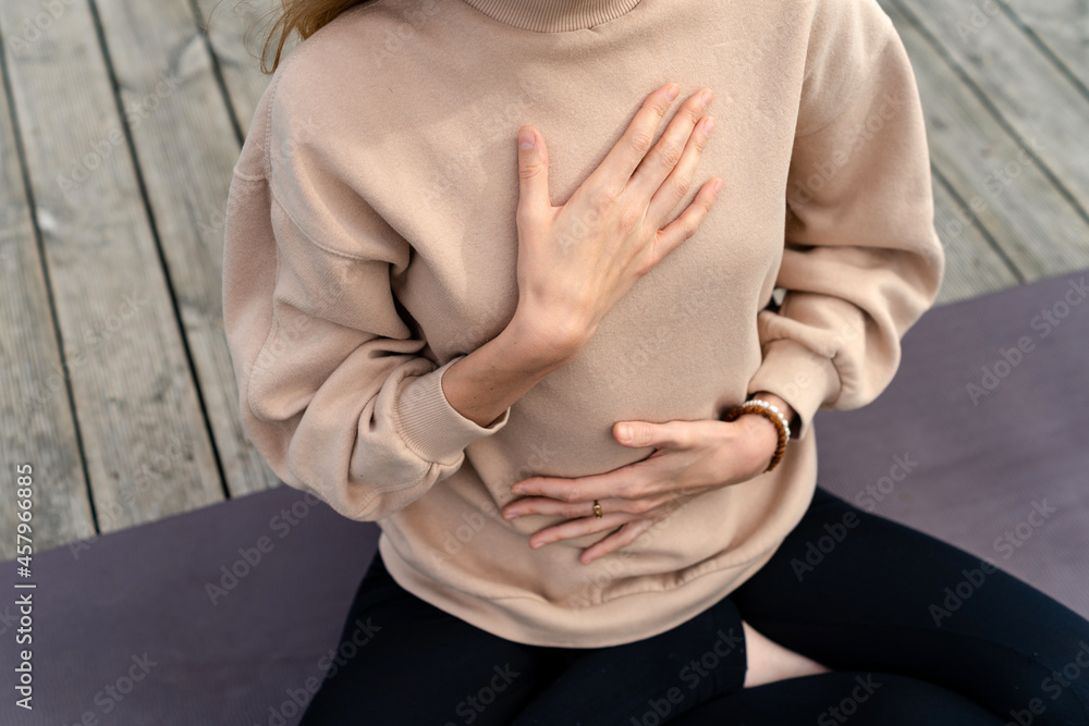 Close-up of a woman's hands on her chest while doing breathing exercises